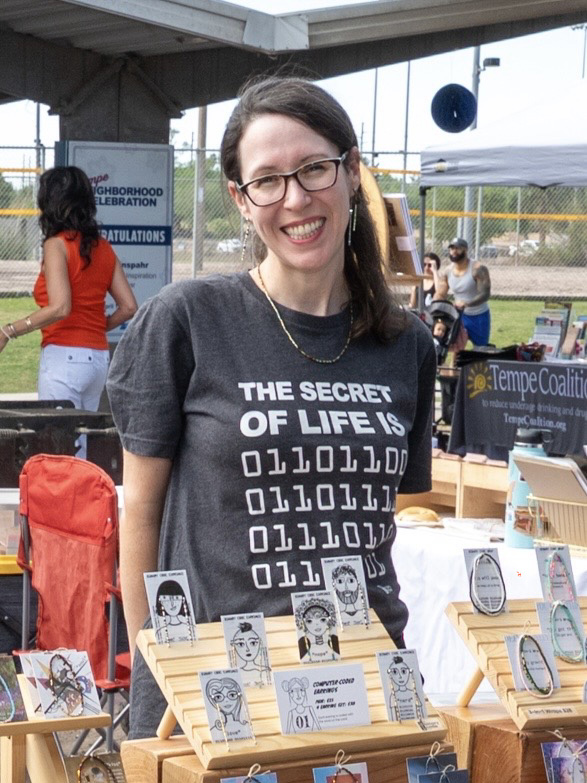 Picture of Melissa standing beside her table at a farmers market